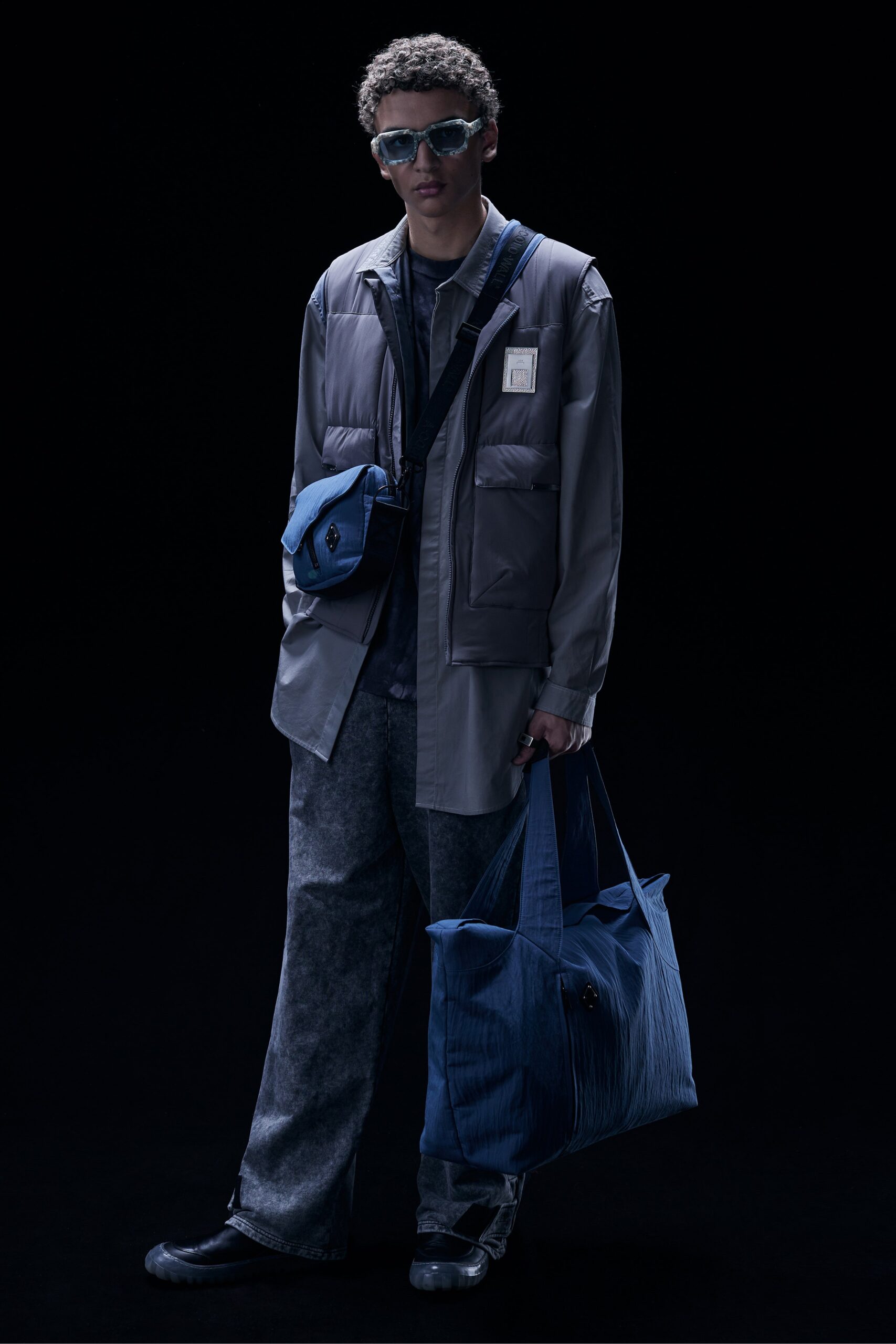 This relaxed jacket features a layered design with a collared neckline, offering a contemporary silhouette. Paired with wide-leg blue pants, the ensemble creates a striking balance between structure and ease, perfect for modern streetwear aesthetics.
