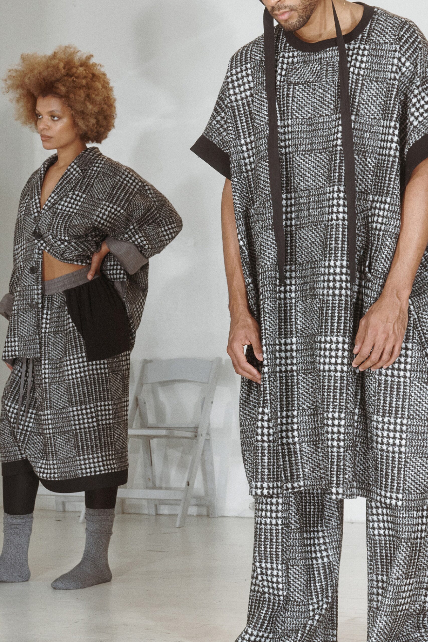 This relaxed coat features a striking checked pattern, offering a contemporary twist on classic tailoring. Paired with matching pants, the ensemble emphasizes a fluid silhouette that balances structure with ease, creating a modern aesthetic.