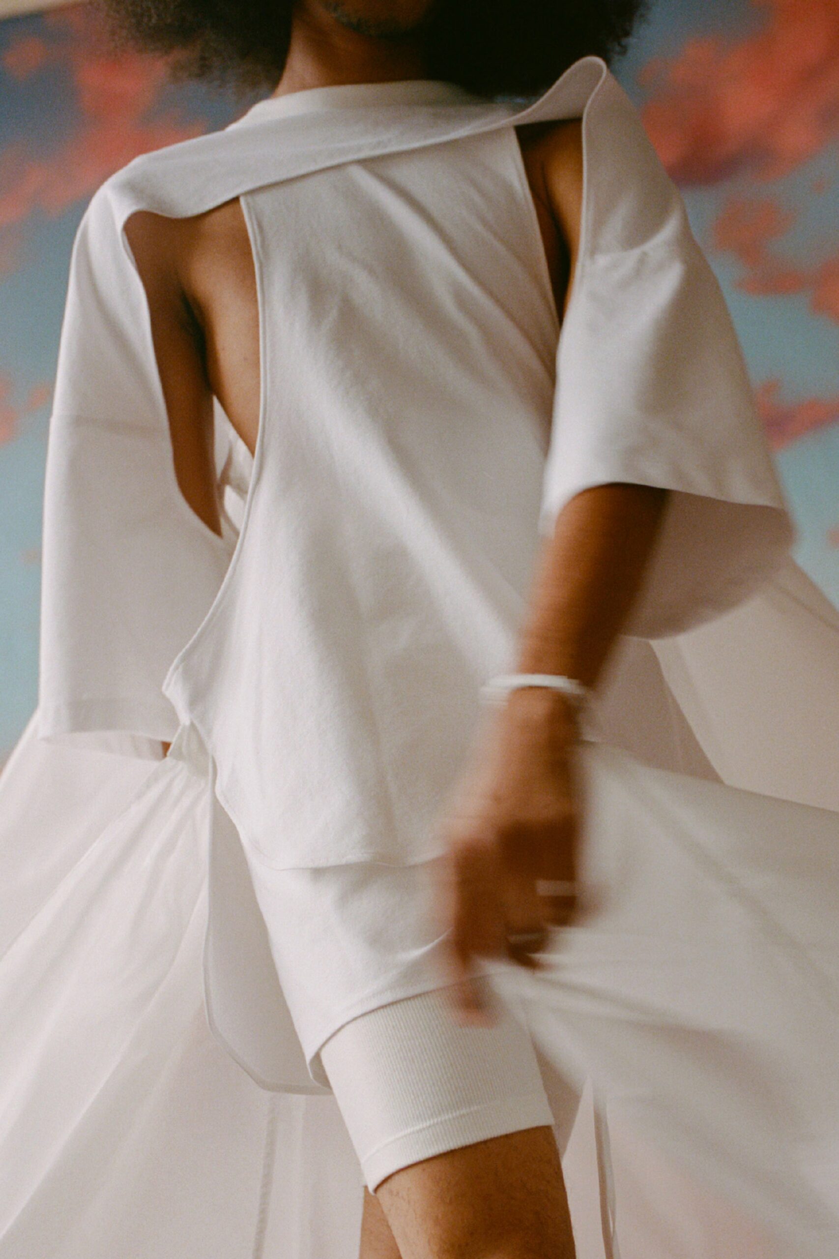 This dress features a relaxed silhouette with a high-neck design, enhanced by asymmetric layers that create a dynamic flow. The interplay of textures adds depth, while the sleeveless construction allows for effortless movement.