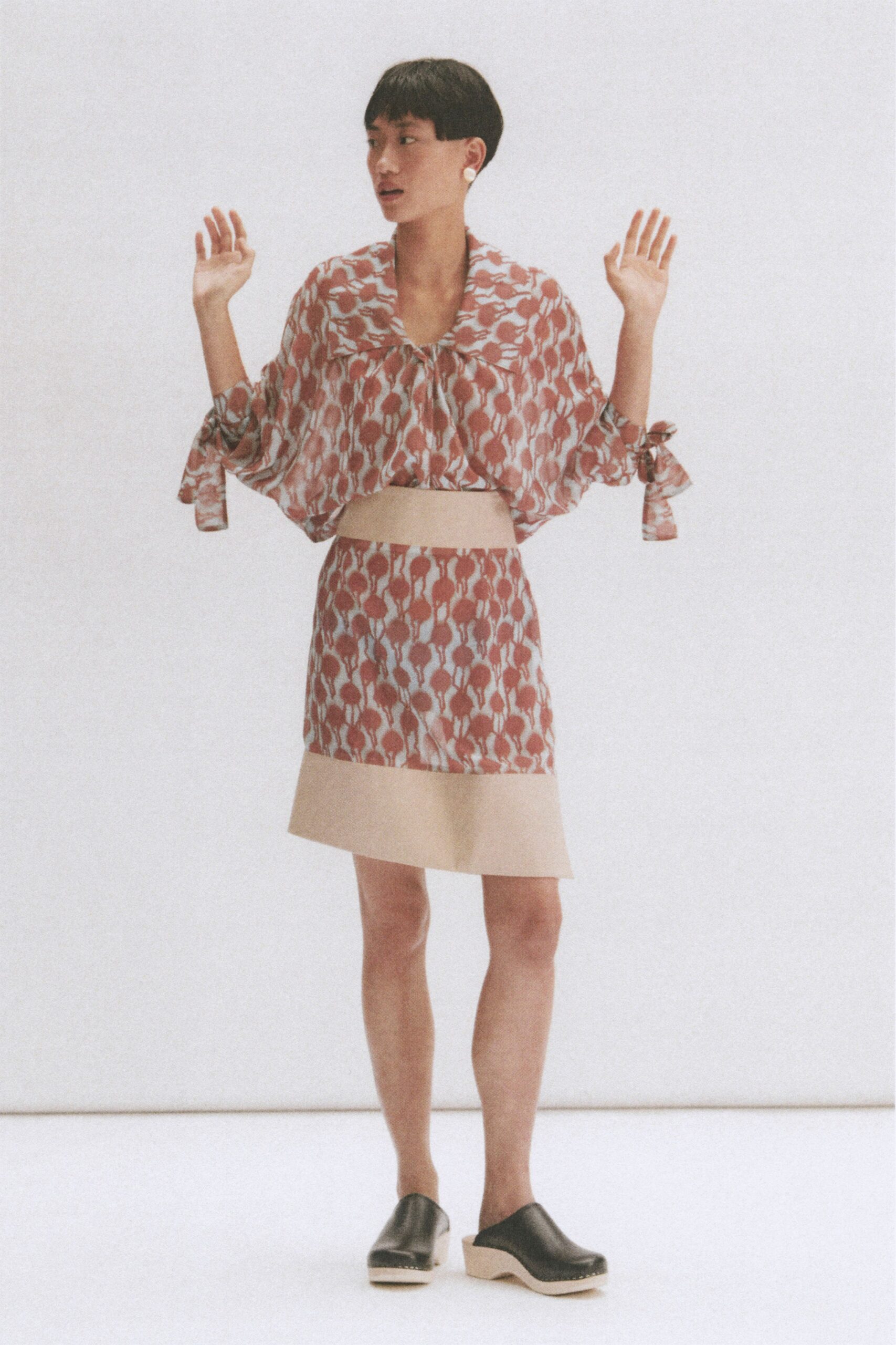 red and white printed top with beige mini skirt