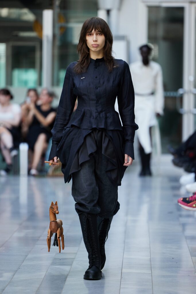 A fitted black blouse with ruffled details paired with black pants for a chic look.