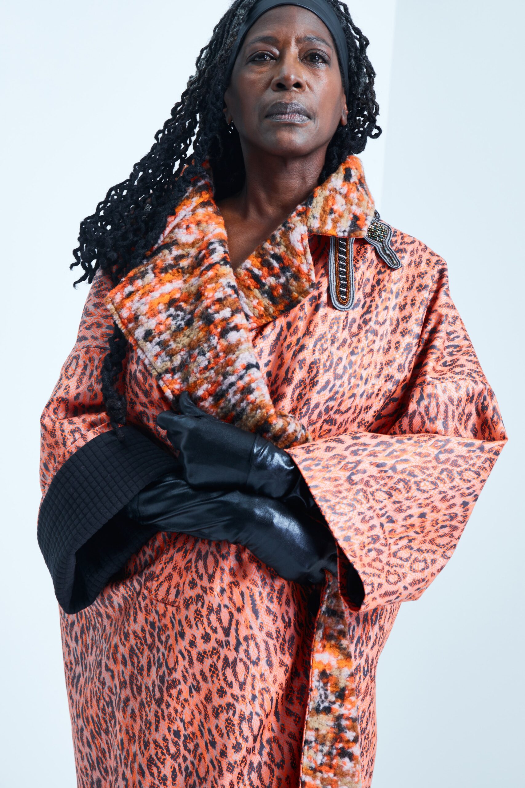 This coat features a striking animal-print design in vibrant orange and black hues, creating a bold visual statement. The relaxed fit and layered construction enhance its dramatic silhouette, while the long sleeves and collared neckline add structure to the overall look.