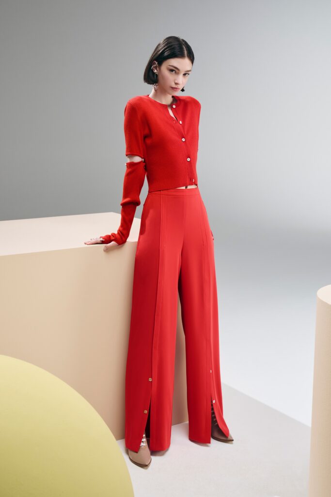A fitted red long-sleeve top with collared detail paired with wide-leg pants featuring button accents.