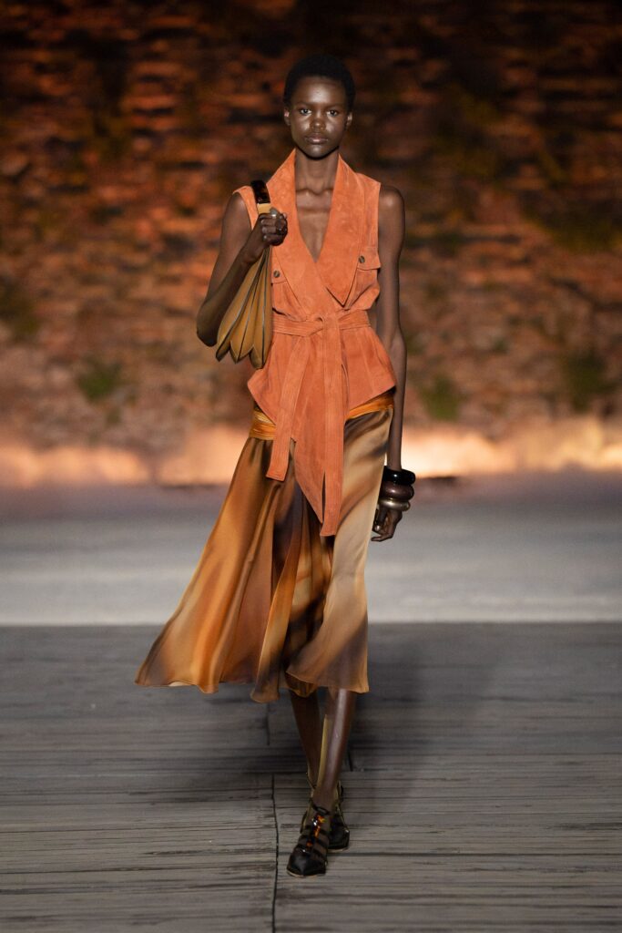 A fitted sleeveless dress with a V-neckline, layered asymmetric design in orange and brown hues.