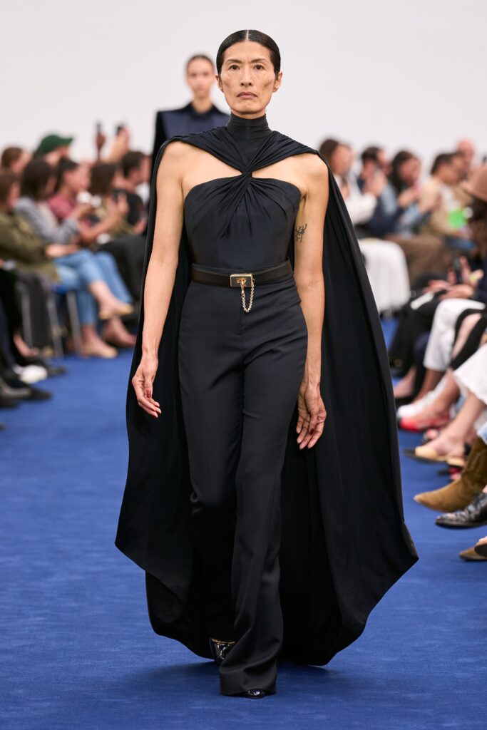 A fitted black silk jumpsuit with a high-neck and asymmetric design detail.