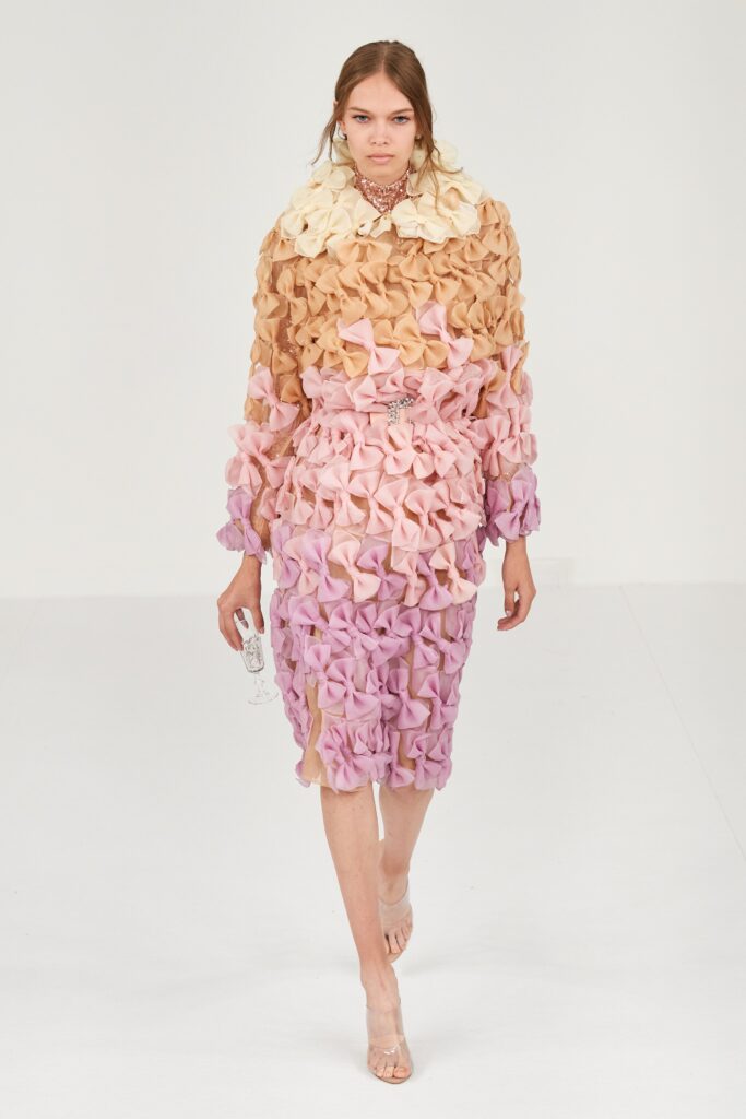A fitted long-sleeve dress in pink, beige, and cream with a ruffled layered design.