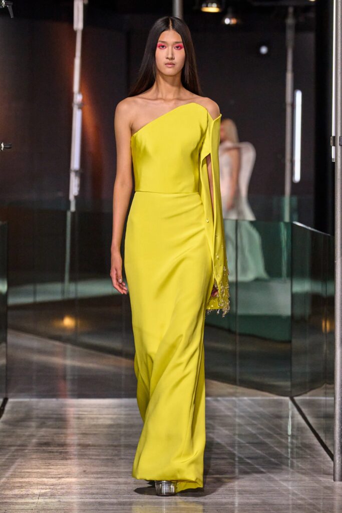 A fitted yellow silk gown with an asymmetric design and a high neckline.