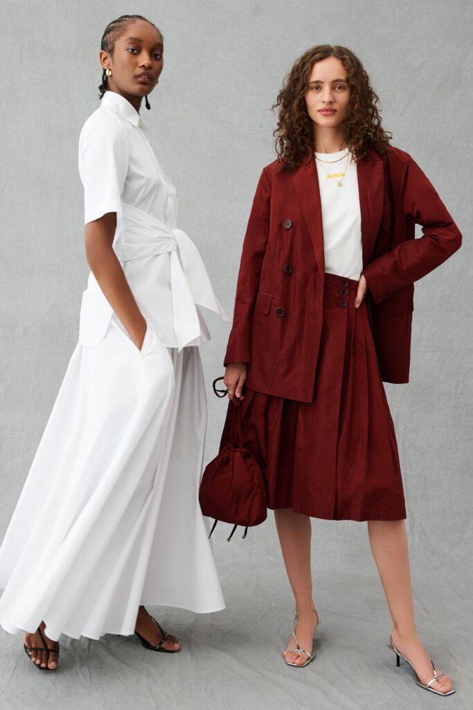 A fitted white dress paired with a burgundy jacket featuring short sleeves and pleated details.