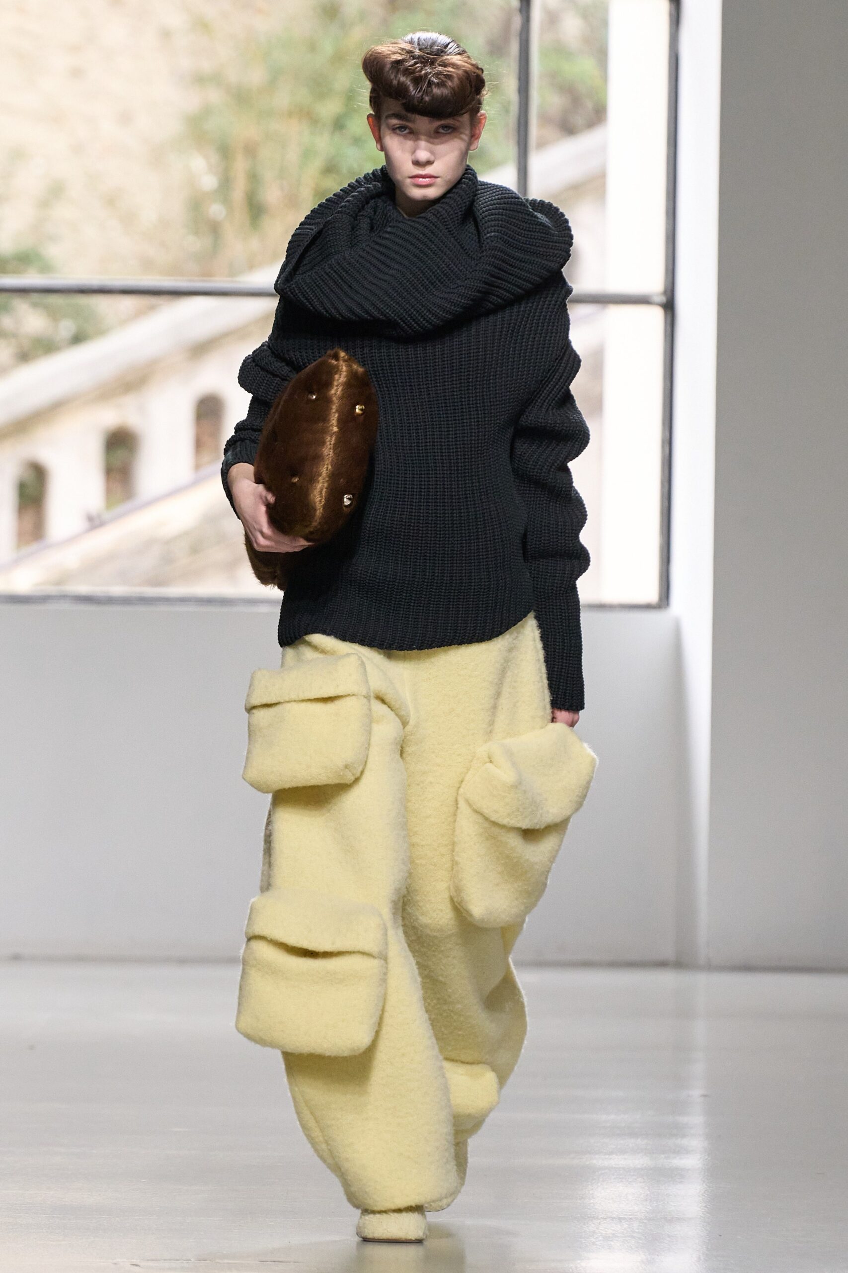 An oversized black sweater with long sleeves paired with yellow pocketed pants.