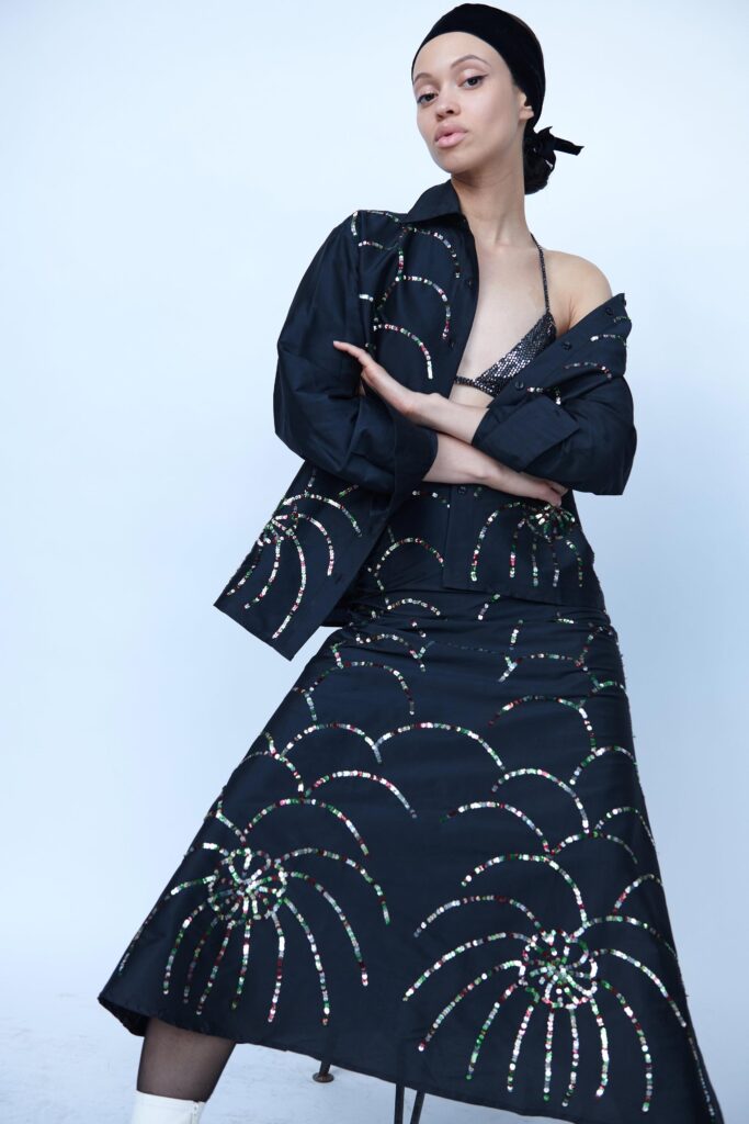 A fitted black sleeveless dress with an embroidered design and a V-neckline.