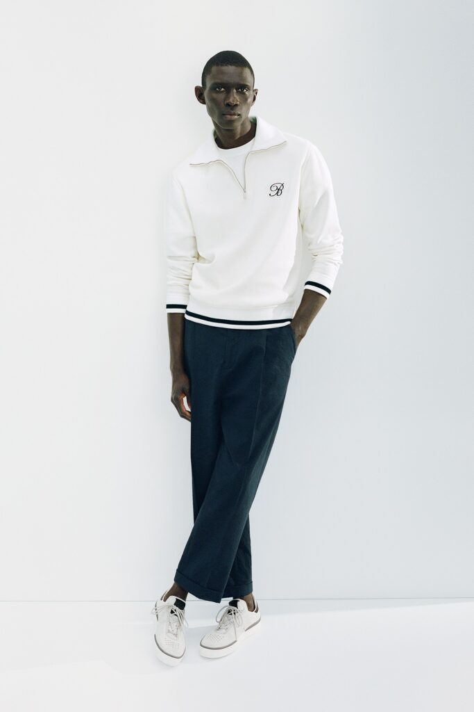 A relaxed white long-sleeve sweater with a collar paired with navy pants.