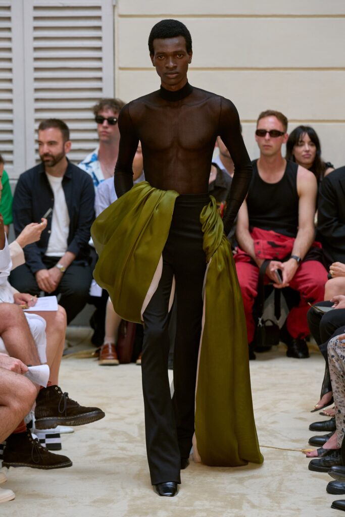 A fitted black silk top with a V-neck and asymmetric design paired with sleek pants.