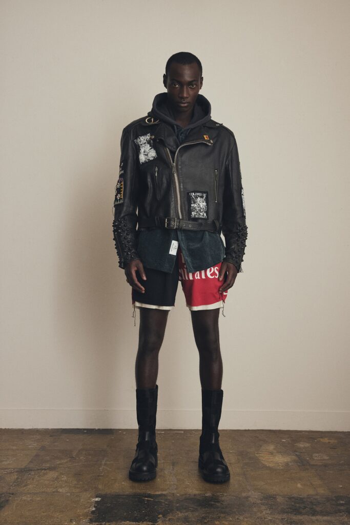 A fitted black leather jacket with long sleeves and a collared design paired with printed red shorts.