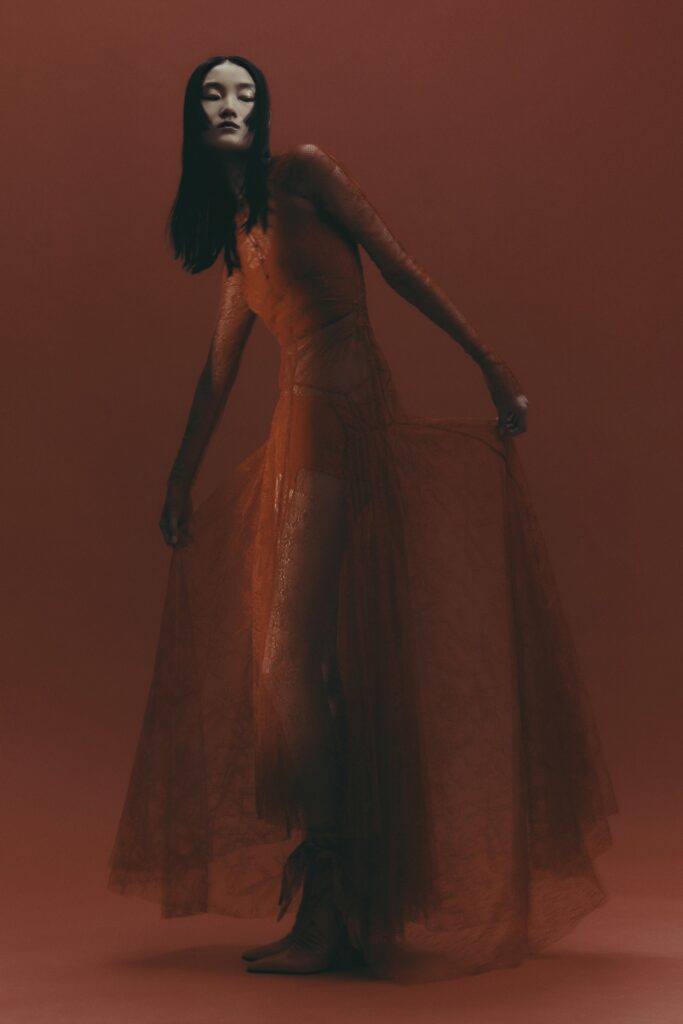A fitted orange lace long-sleeve dress with a V-neckline and tiered design.