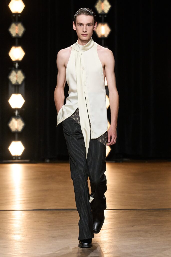 A fitted white sleeveless shirt paired with black striped pants, creating a sleek runway look.
