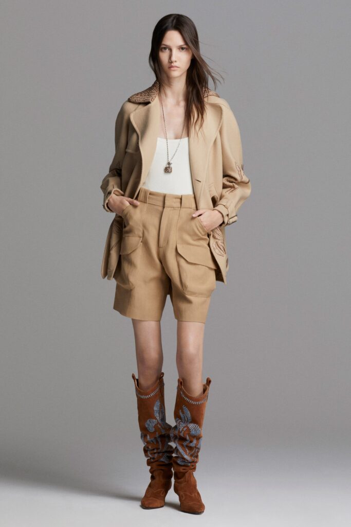 A relaxed beige cotton jacket with long sleeves and pleated shorts, perfect for a casual look.