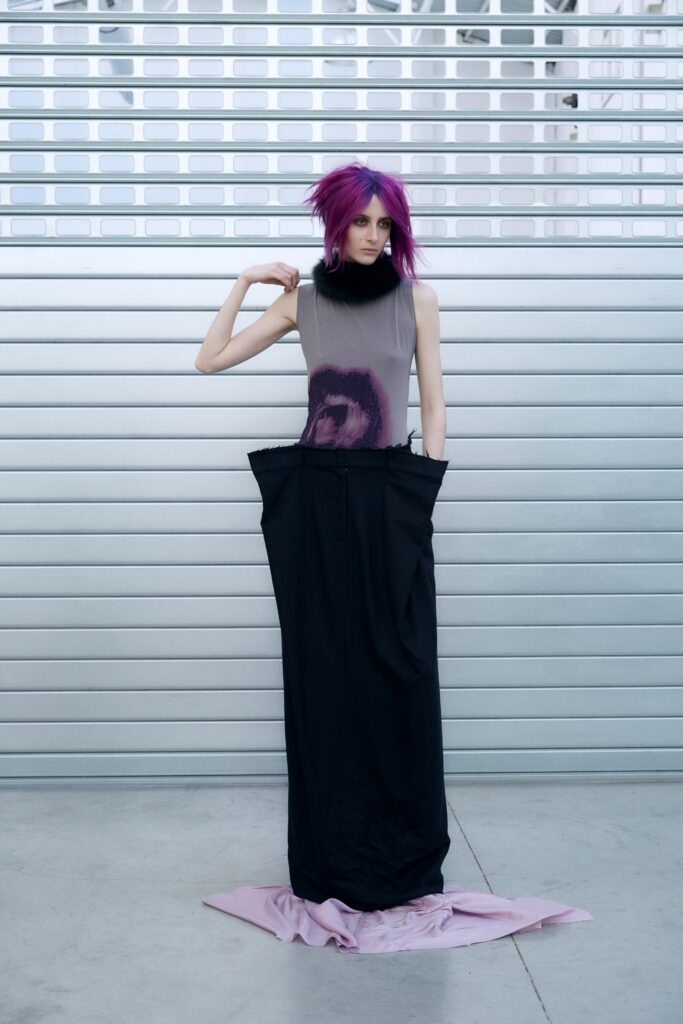 A fitted black and purple sleeveless dress with a high-neck and asymmetric design detail.