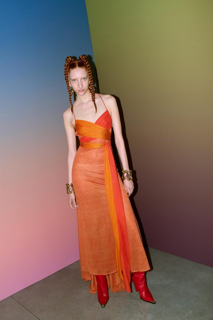 A fitted orange silk dress with a sleeveless design and asymmetric detailing.