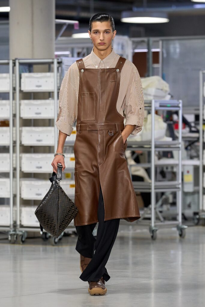 A fitted brown leather dress with long sleeves and a collared neckline featuring an asymmetric design.