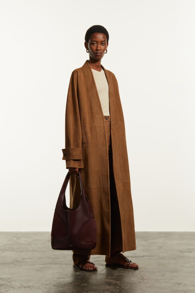 A relaxed brown suede coat with long sleeves and a collared design, paired with straight-leg pants.