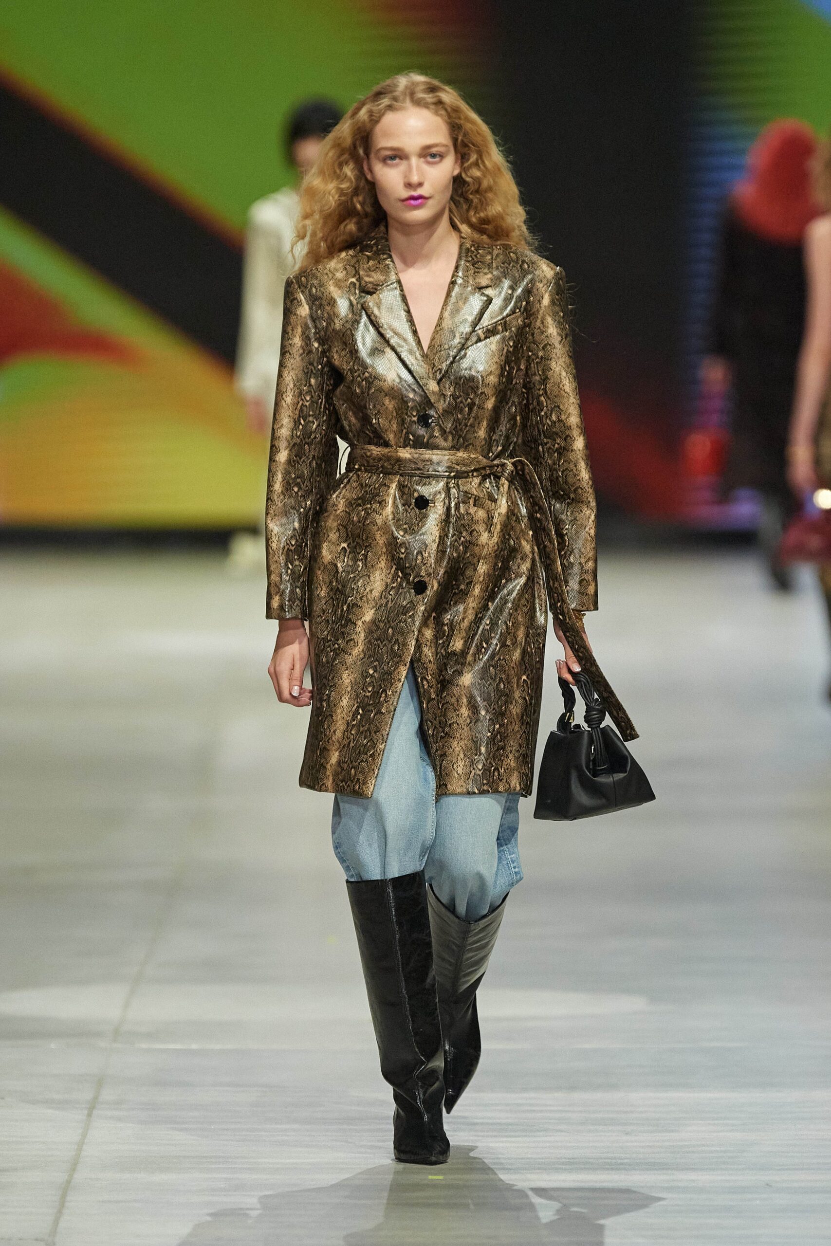 A fitted gold silk coat with long sleeves, layered over denim pants.