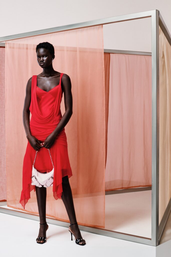 A fitted red silk dress with a sleeveless design and draped detailing.