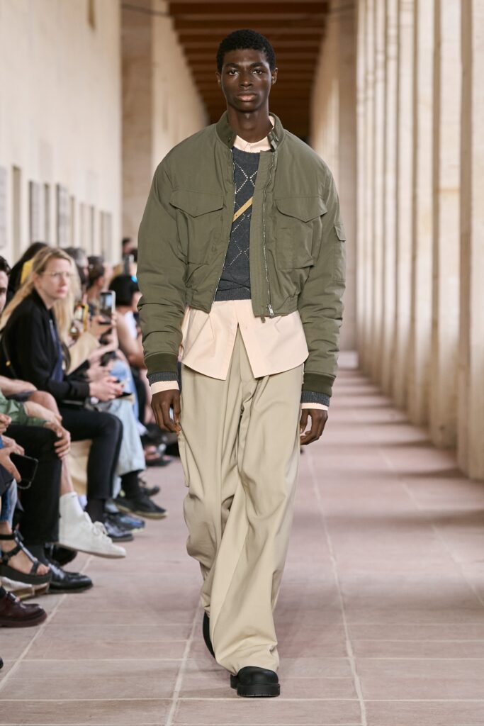 A relaxed green cotton jacket with long sleeves paired with beige pants.