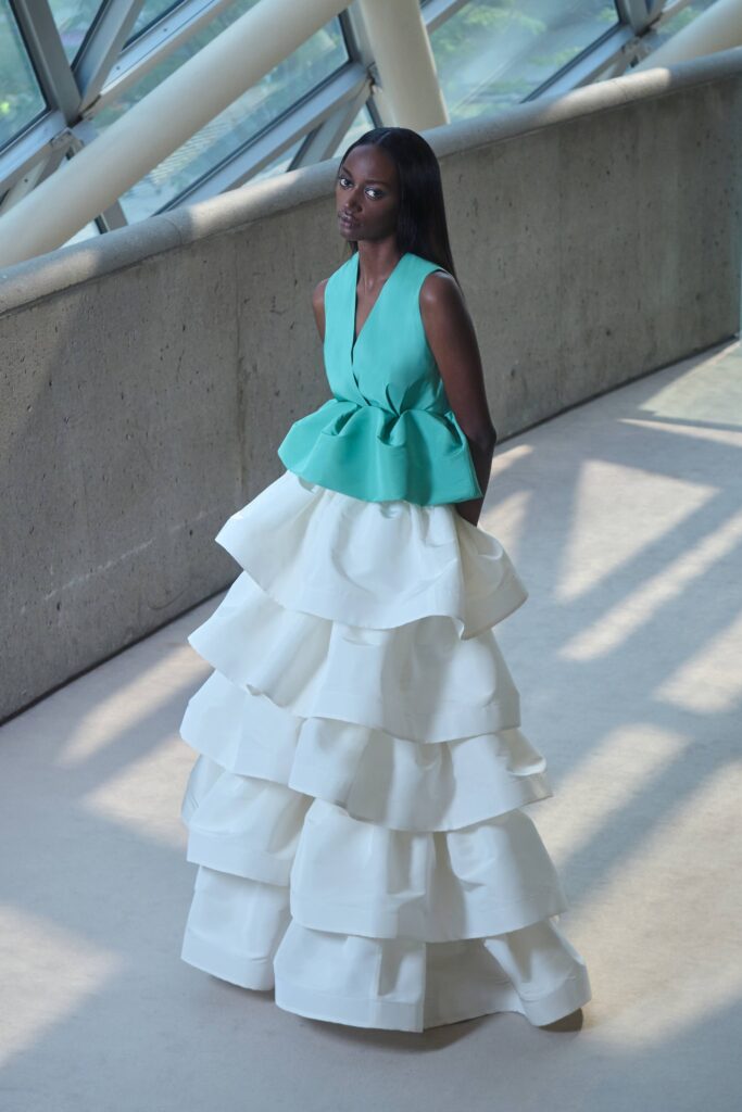 A fitted green sleeveless dress with a V-neckline and a tiered white skirt.
