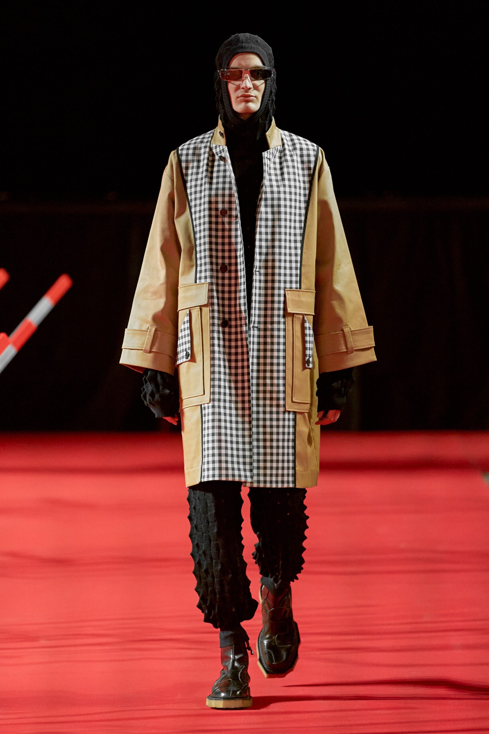 A relaxed beige checked coat paired with black pants, showcasing a modern streetwear aesthetic.