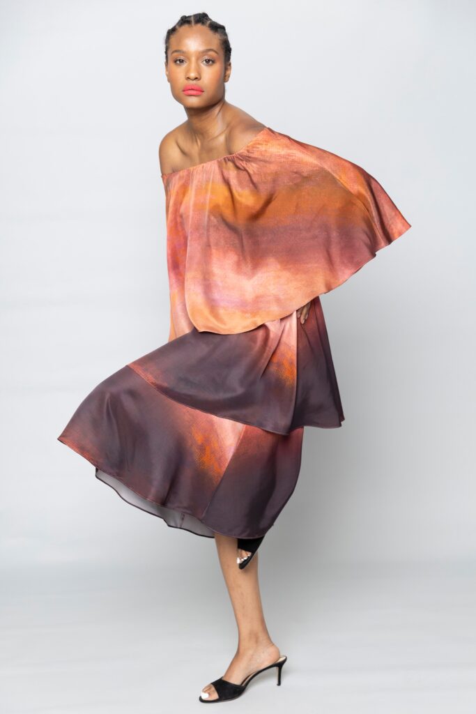 A relaxed off-shoulder dress in orange and black with an asymmetric layered design.