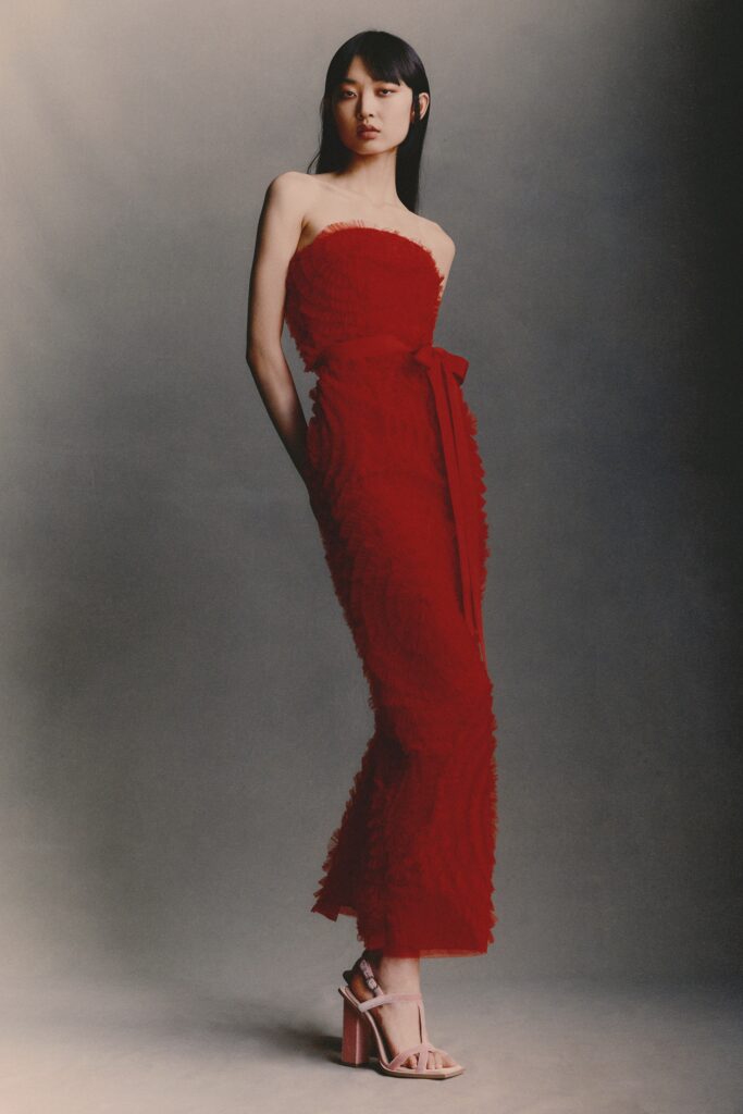 A fitted red strapless dress with a tiered design and elegant silhouette.