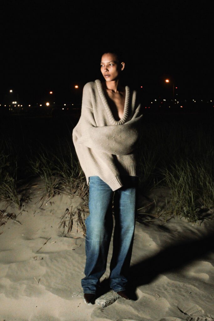 An oversized beige sweater with a V-neck paired with straight-leg blue jeans.