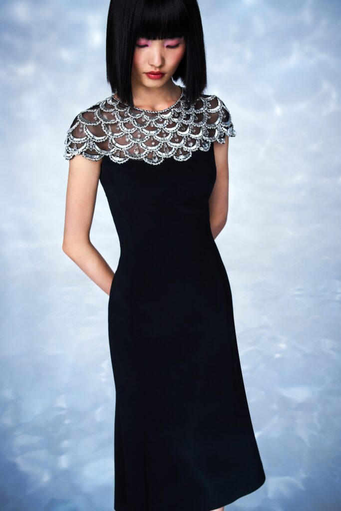 A fitted black silk dress with a high-neck and beaded detailing at the neckline.