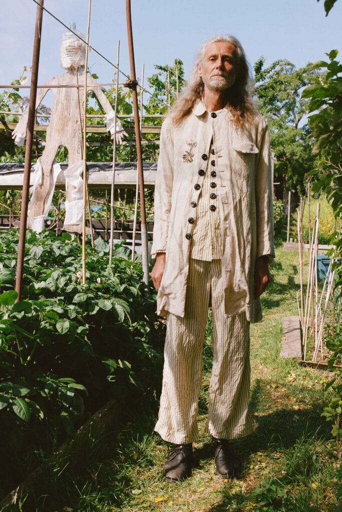 A relaxed beige cotton jacket with long sleeves and collared design, paired with striped pants.