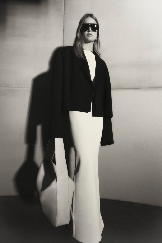 A fitted white dress paired with a black long-sleeve jacket, featuring a V-neckline.