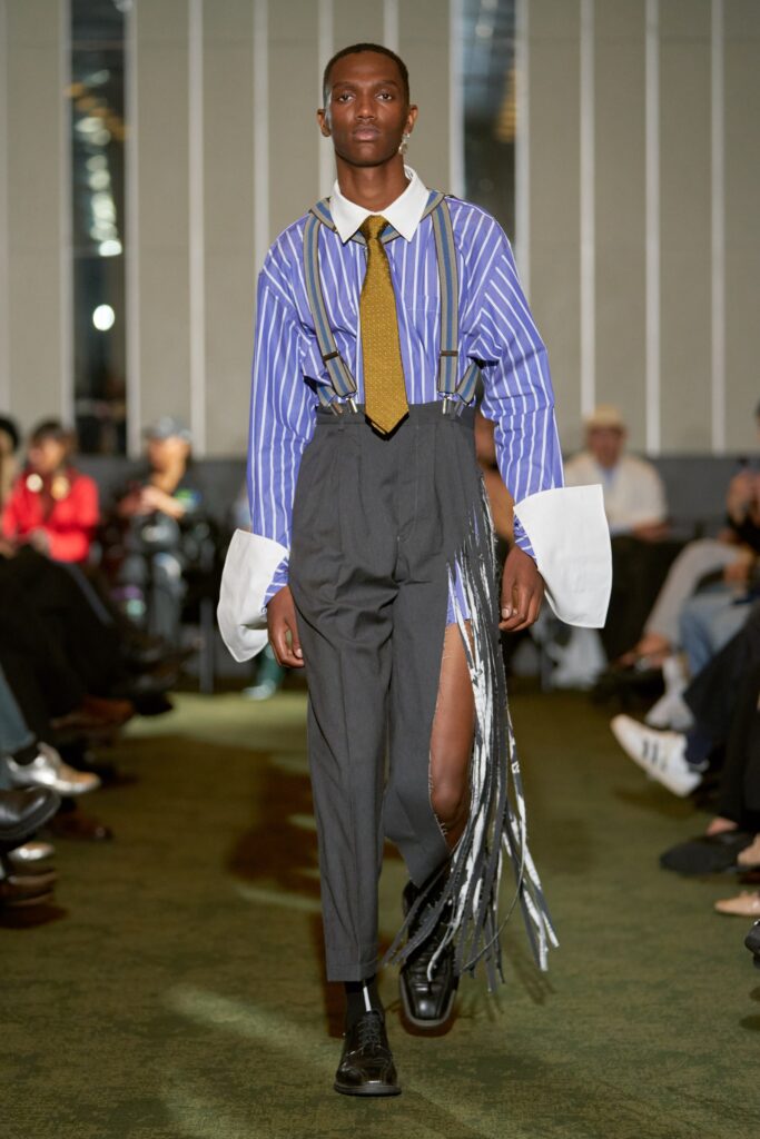 A relaxed blue striped shirt with long sleeves paired with gray pants featuring an asymmetric design.