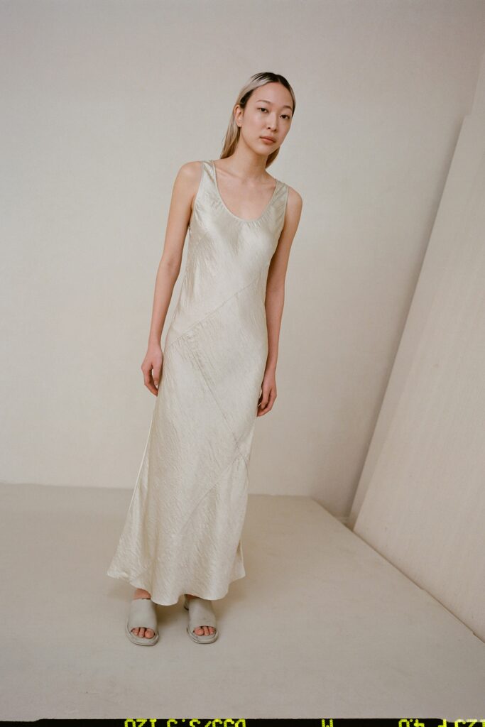 A fitted cream silk sleeveless dress with a V-neckline and maxi silhouette.