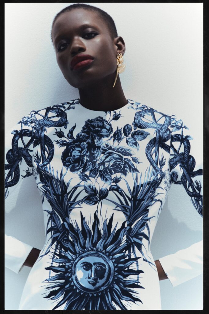 A fitted white and blue printed dress with long sleeves and a high neckline.