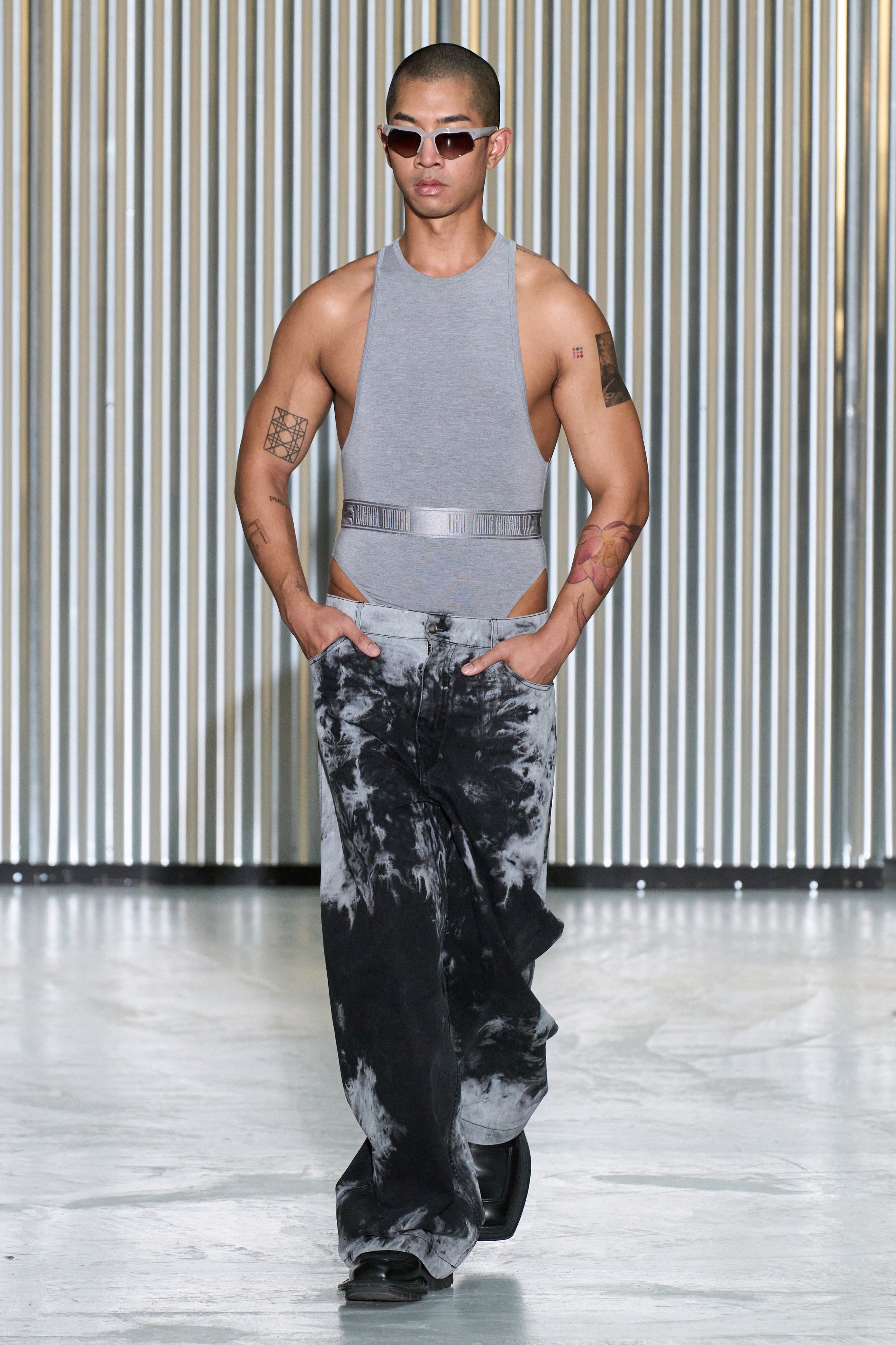 A fitted gray sleeveless top paired with flared black denim pants for a modern look.