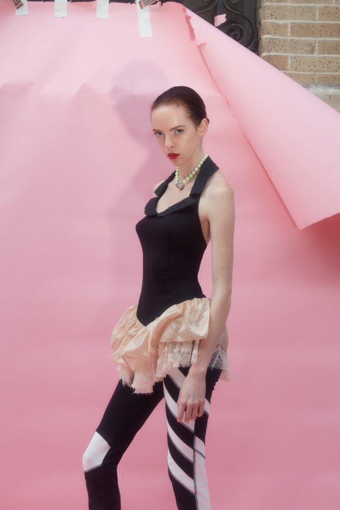A fitted black sleeveless top with layered pink details and fitted pants.