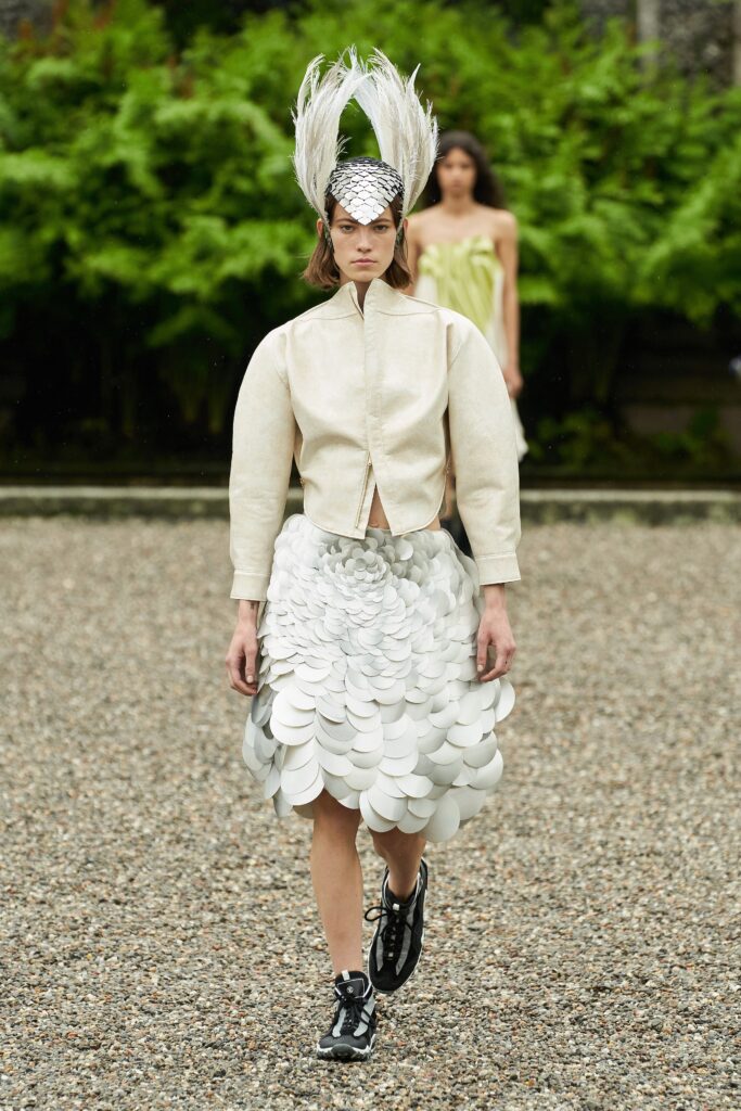 A fitted white leather jacket paired with a layered skirt, showcasing a unique fashion statement.