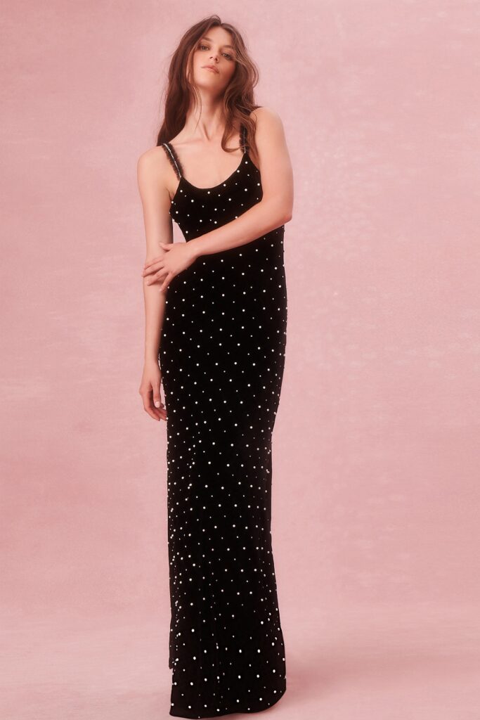 A fitted black velvet sleeveless dress with a V-neckline and tiered design.