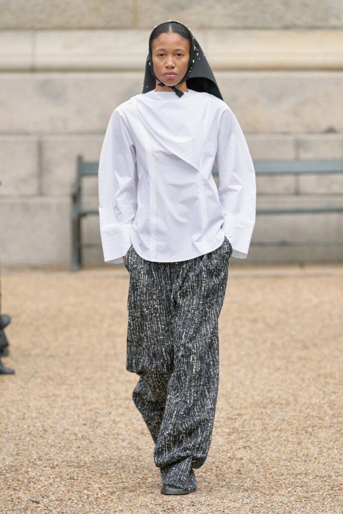 A relaxed white long-sleeve collared shirt paired with printed black pants.