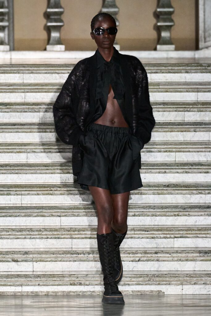 A relaxed black cotton top with a collared design paired with pleated black shorts.