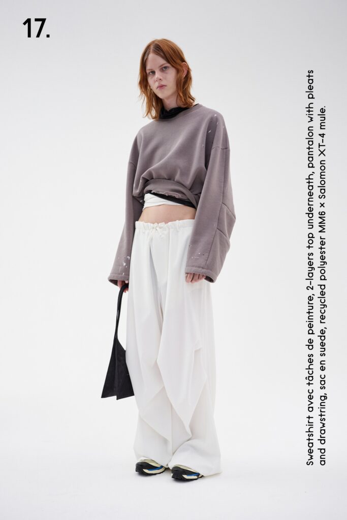 A relaxed gray long-sleeve sweater paired with high-waisted pleated white pants.