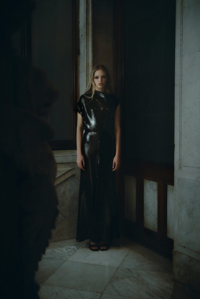 A fitted black silk dress with a sleeveless design and high-neck construction.