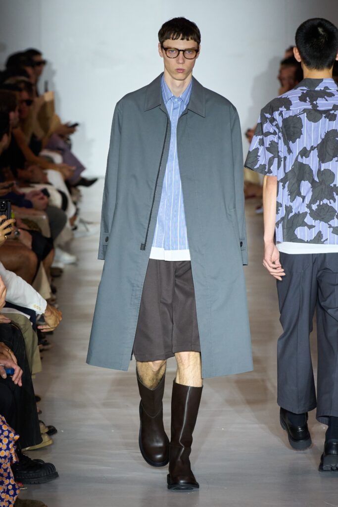 A relaxed gray coat layered over a blue collared shirt, creating a stylish ensemble.