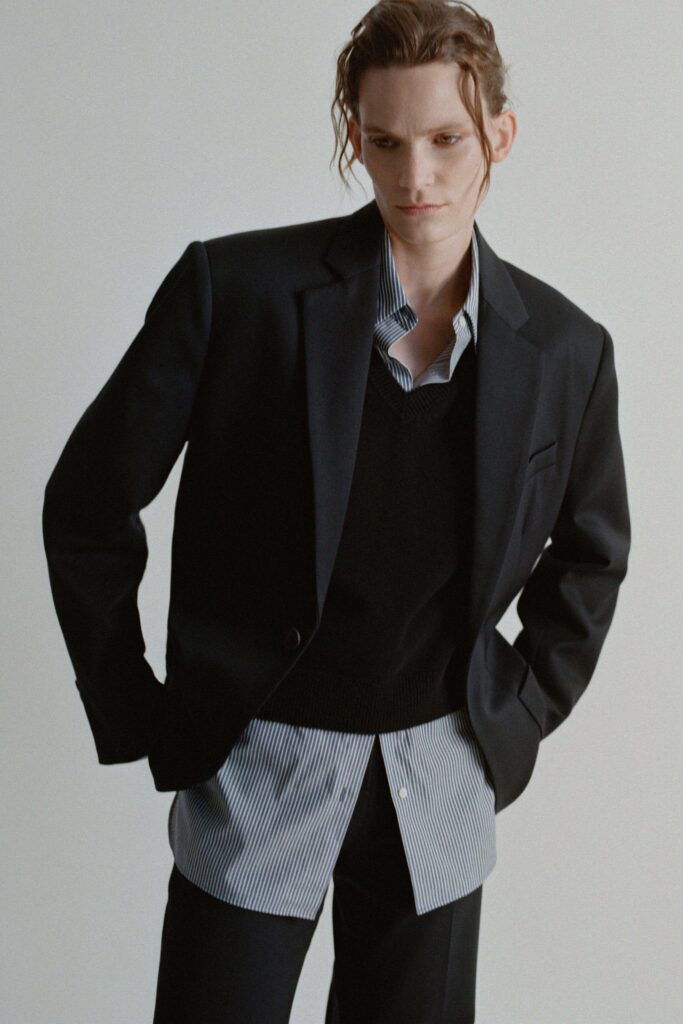A fitted black blazer layered over a collared striped shirt, creating a stylish ensemble.