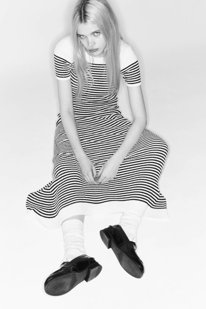 A fitted black and white striped dress with a V-neckline and short sleeves.