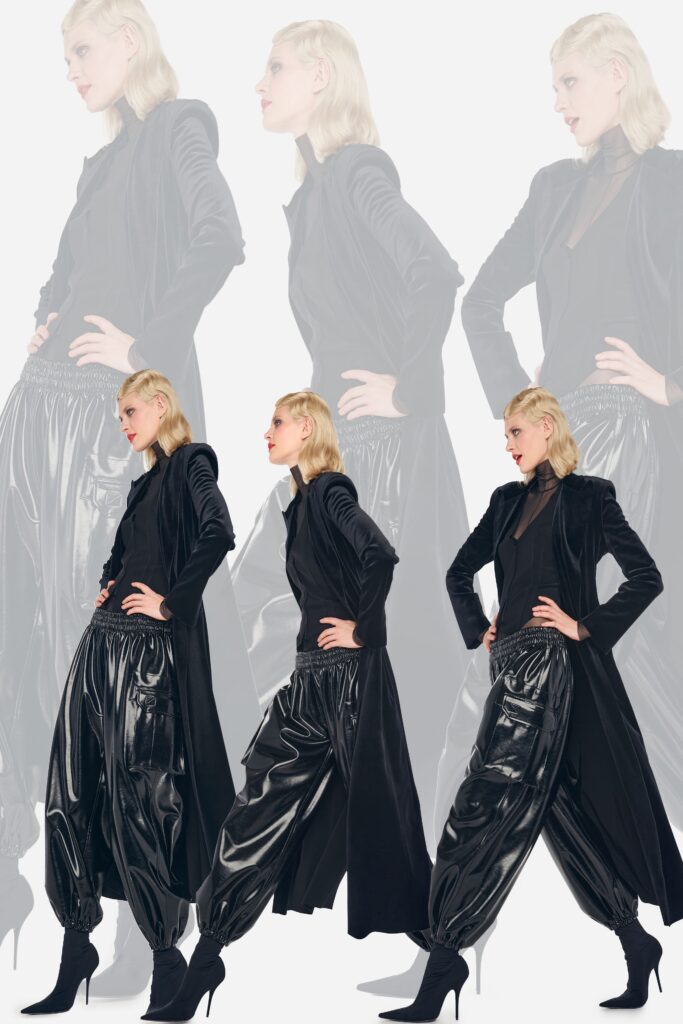 A relaxed black leather coat with long sleeves and pleated pants featuring a zippered detail.